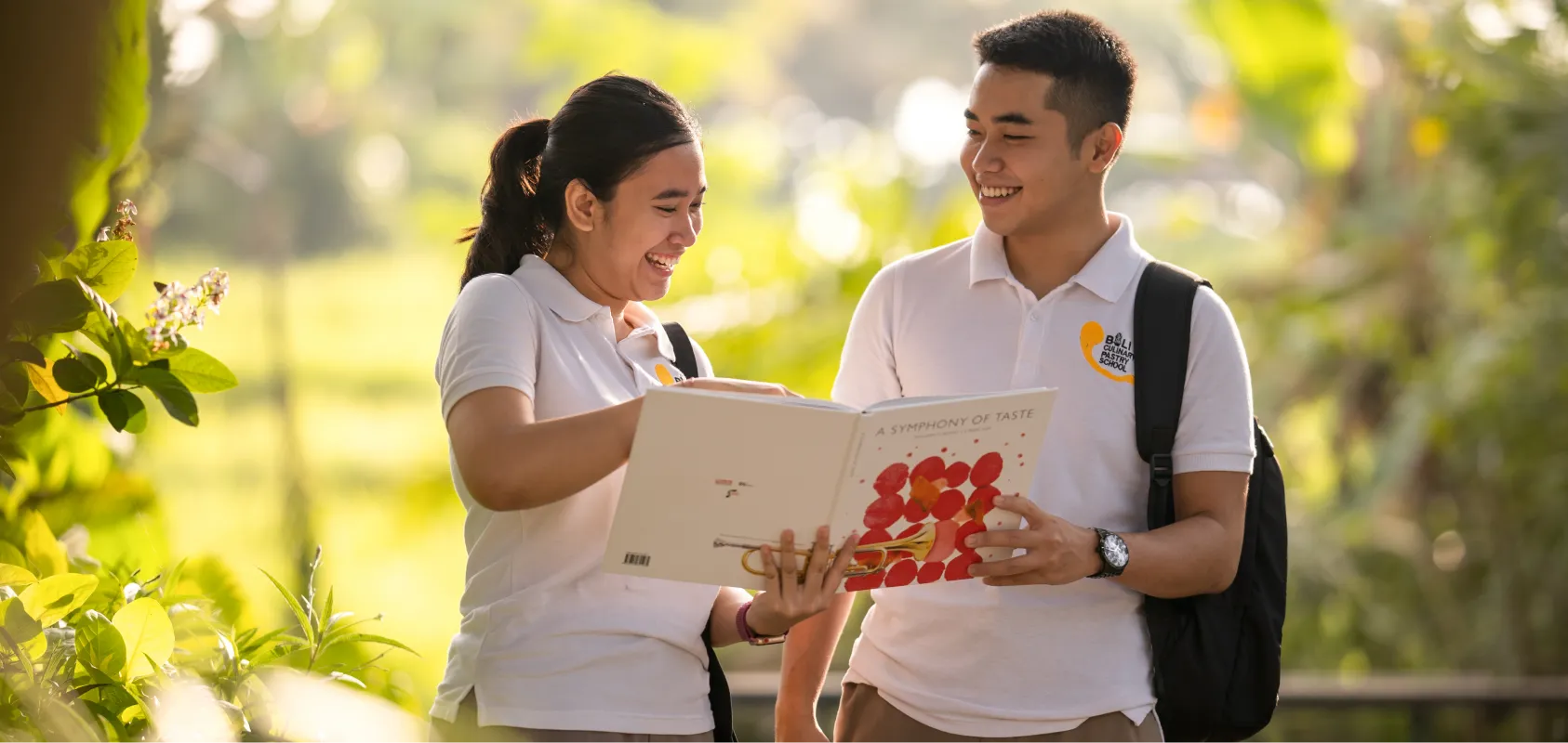 Two students looking at a book together outdoors